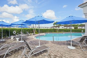 a swimming pool with umbrellas and chairs around it at The Falls of Portofino Apartment, Naples, FL